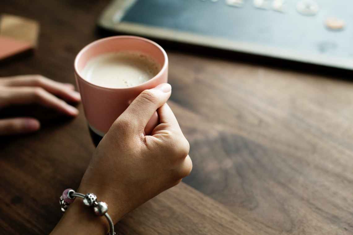 person holding pink ceramic mug