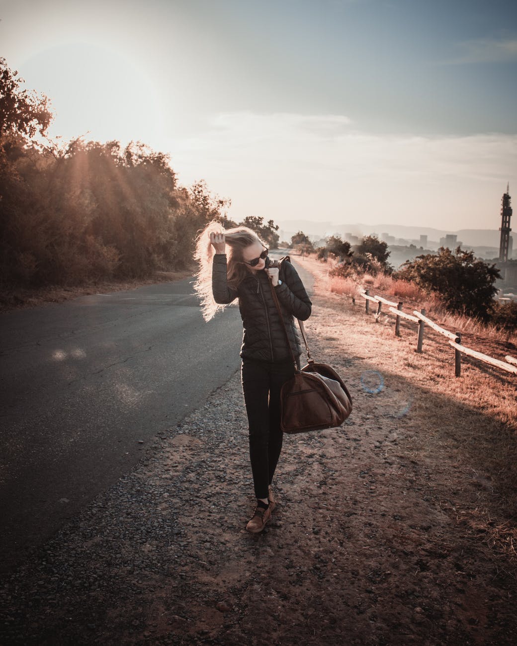 photo of woman walking while holding her hair